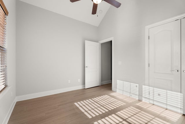 unfurnished bedroom featuring ceiling fan, hardwood / wood-style floors, high vaulted ceiling, and a closet