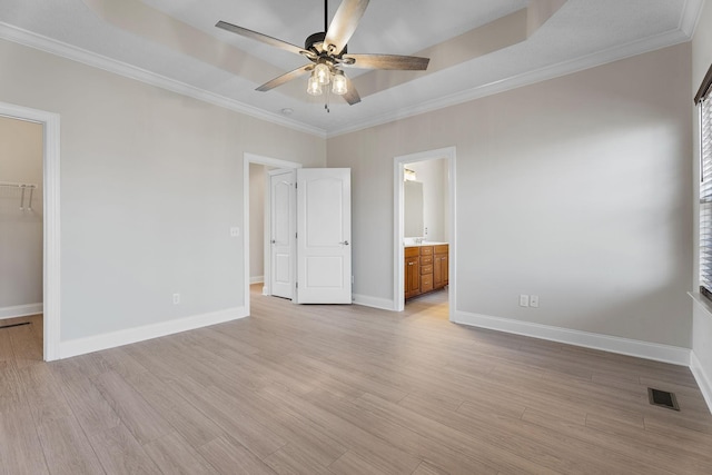 unfurnished bedroom with light wood-type flooring, ornamental molding, a spacious closet, ensuite bath, and a closet