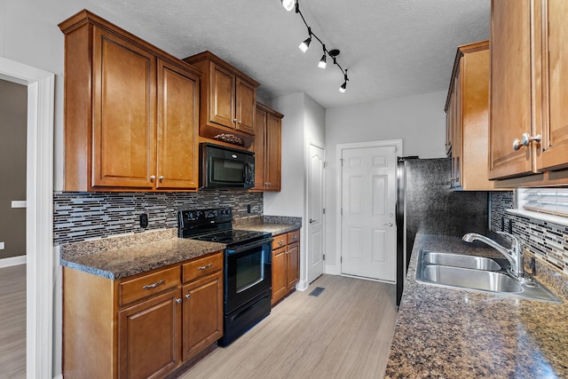 kitchen with light wood-type flooring, sink, decorative backsplash, and black appliances