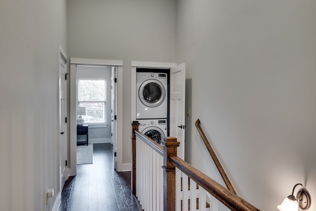 laundry area with stacked washer and dryer and dark hardwood / wood-style flooring