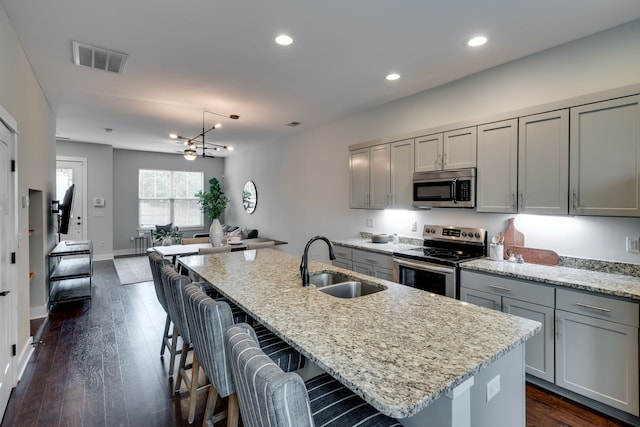 kitchen featuring stainless steel appliances, gray cabinets, sink, and a kitchen island with sink