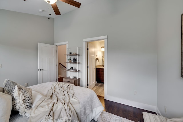 bedroom with connected bathroom, a high ceiling, ceiling fan, and dark hardwood / wood-style floors