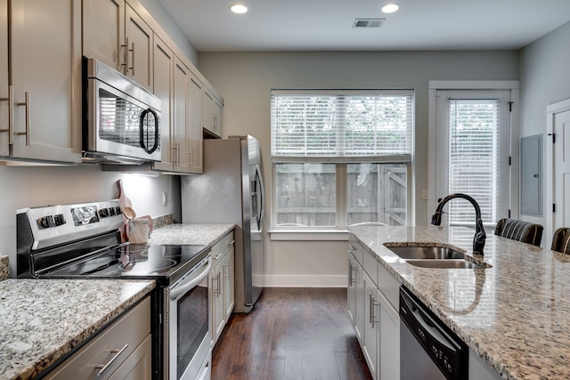 kitchen with dark hardwood / wood-style floors, sink, light stone counters, and appliances with stainless steel finishes