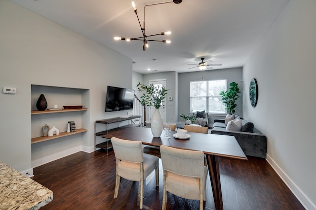 dining room with ceiling fan with notable chandelier and dark hardwood / wood-style floors