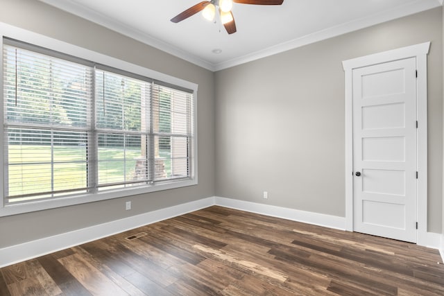 spare room featuring ornamental molding, a wealth of natural light, dark wood-type flooring, and ceiling fan