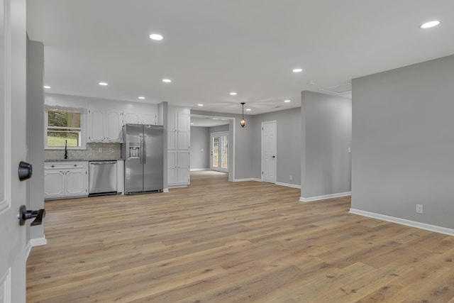 kitchen featuring stainless steel appliances, backsplash, sink, light hardwood / wood-style floors, and white cabinets