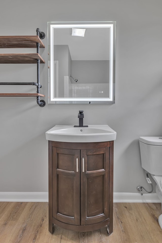 bathroom with wood-type flooring, vanity, and toilet