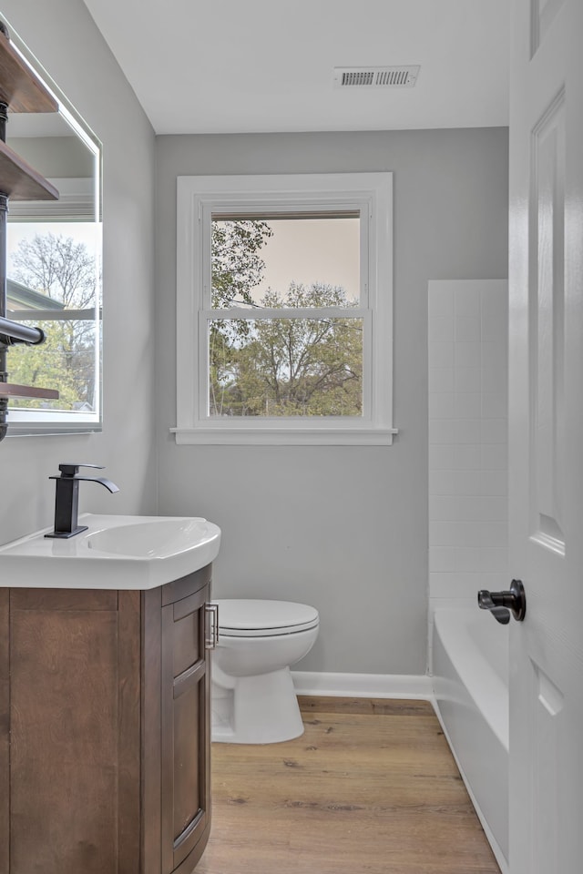 bathroom featuring hardwood / wood-style floors, a bath, vanity, and toilet