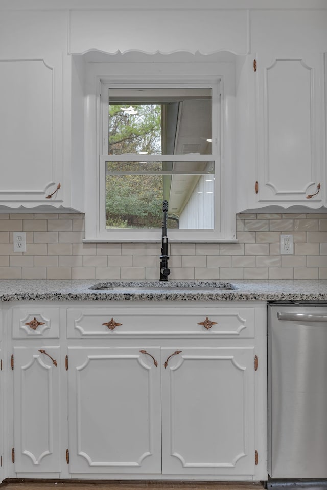 room details with sink, light stone counters, backsplash, stainless steel dishwasher, and white cabinets