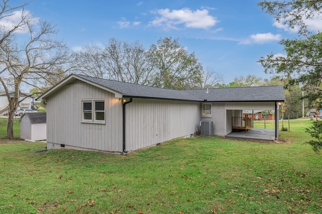 back of property featuring central air condition unit and a yard