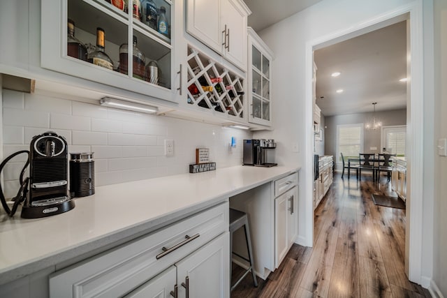 kitchen with white cabinetry, hanging light fixtures, an inviting chandelier, dark hardwood / wood-style flooring, and backsplash