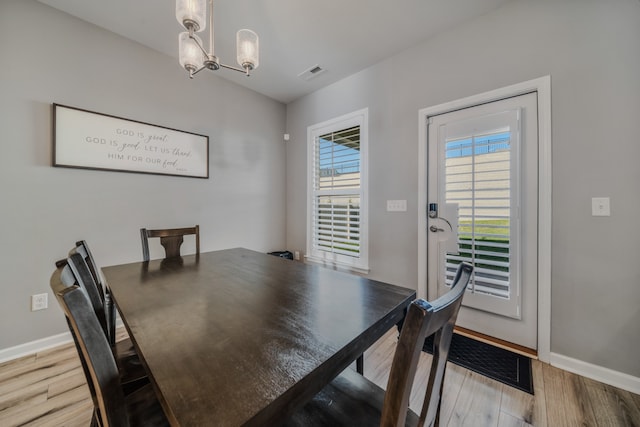 dining space with light hardwood / wood-style flooring and a notable chandelier