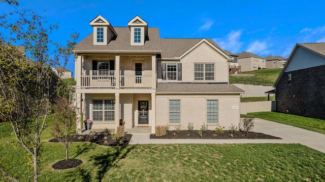 view of front of house featuring a balcony and a front yard