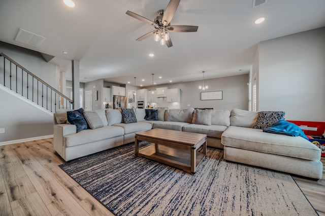 living room featuring light hardwood / wood-style floors and ceiling fan with notable chandelier