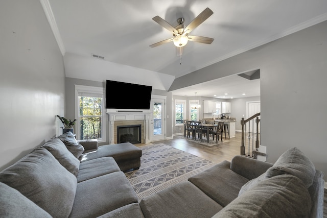 living room featuring ornamental molding, light wood-type flooring, a wealth of natural light, and ceiling fan