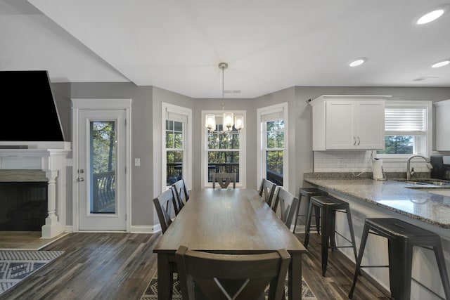 dining space featuring dark hardwood / wood-style flooring, an inviting chandelier, and sink