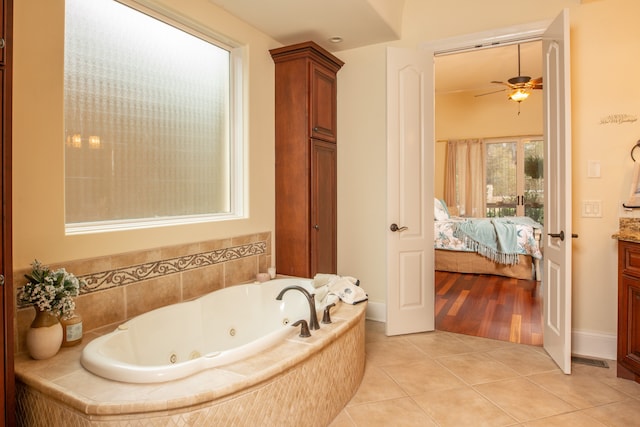 bathroom featuring ceiling fan, vanity, tile patterned floors, and tiled tub