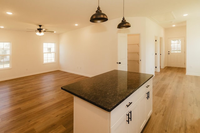 kitchen with light wood-type flooring, white cabinetry, plenty of natural light, and dark stone countertops