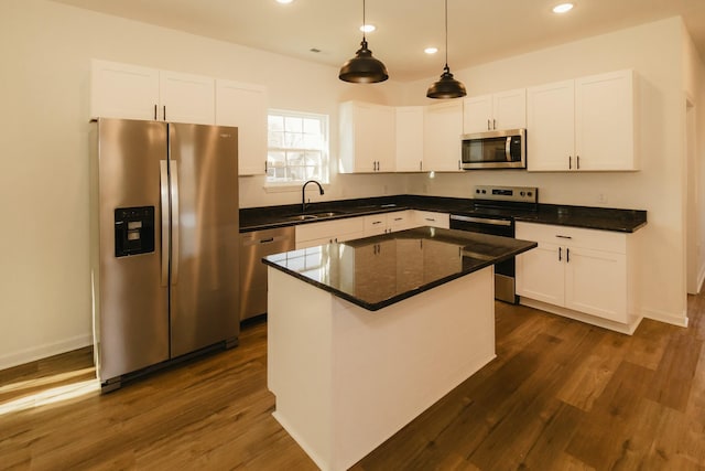 kitchen with sink, a kitchen island, dark hardwood / wood-style flooring, white cabinetry, and stainless steel appliances