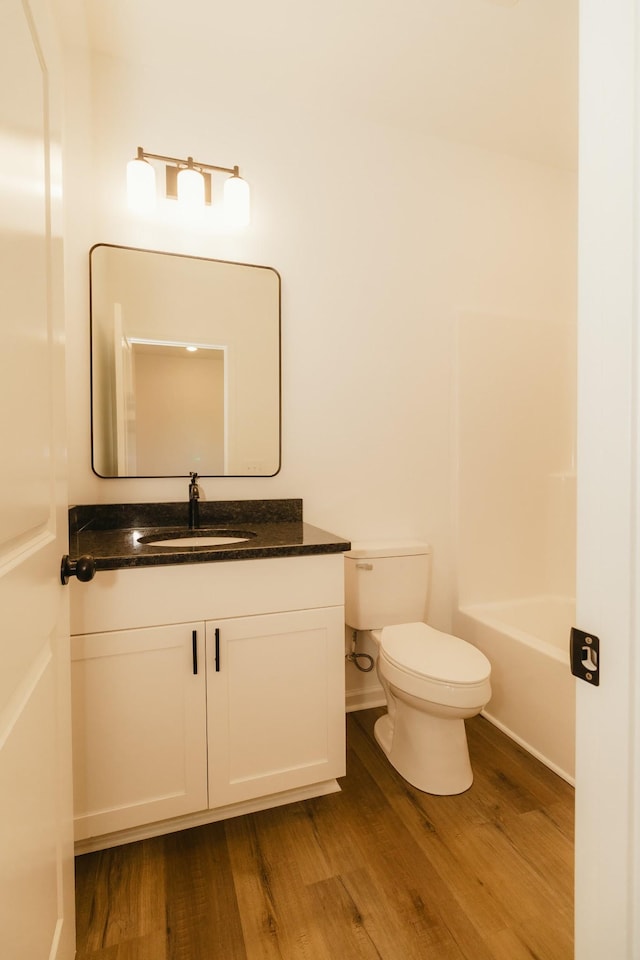 bathroom with hardwood / wood-style flooring, vanity, and toilet