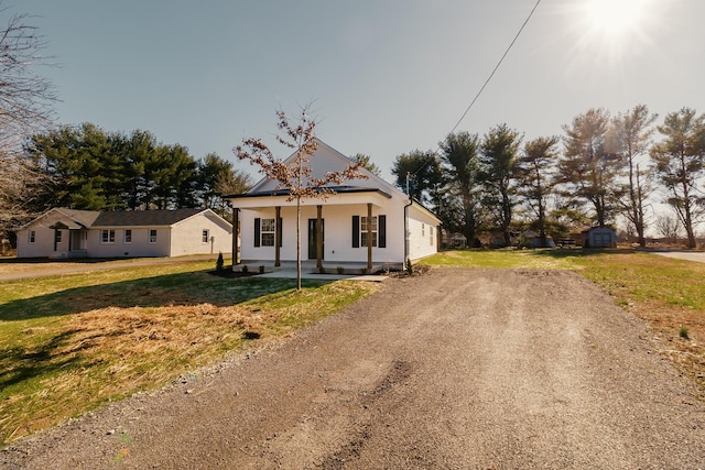 view of front of property featuring a front lawn, a porch, and a storage unit