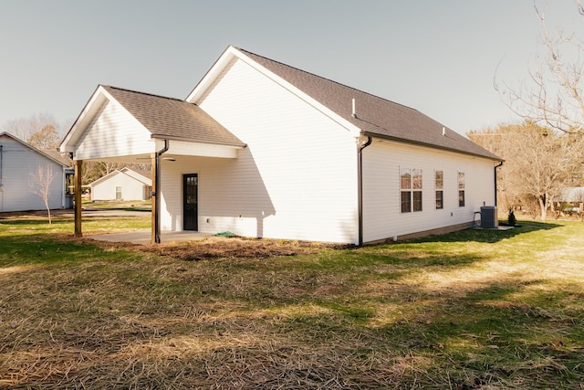 rear view of house with central AC and a lawn