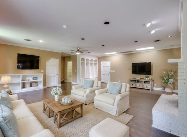 living room featuring hardwood / wood-style floors, ceiling fan, a fireplace, and crown molding