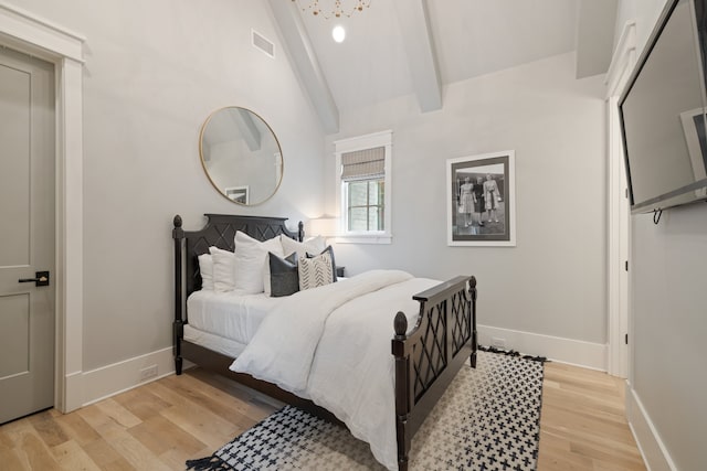 bedroom featuring lofted ceiling with beams and light hardwood / wood-style flooring