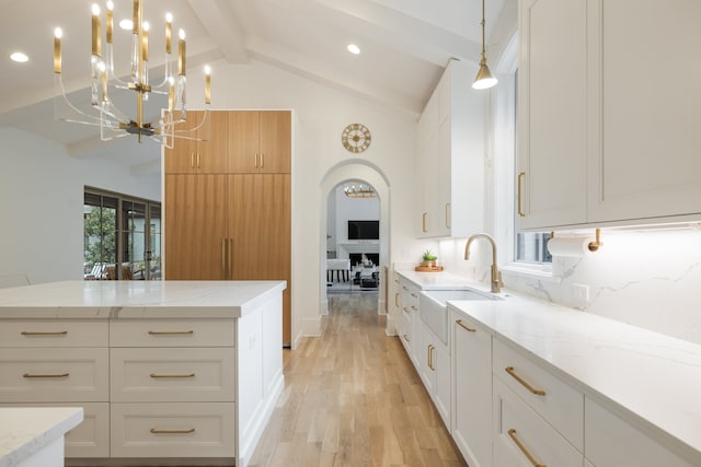 kitchen with white cabinets, sink, pendant lighting, and vaulted ceiling with beams