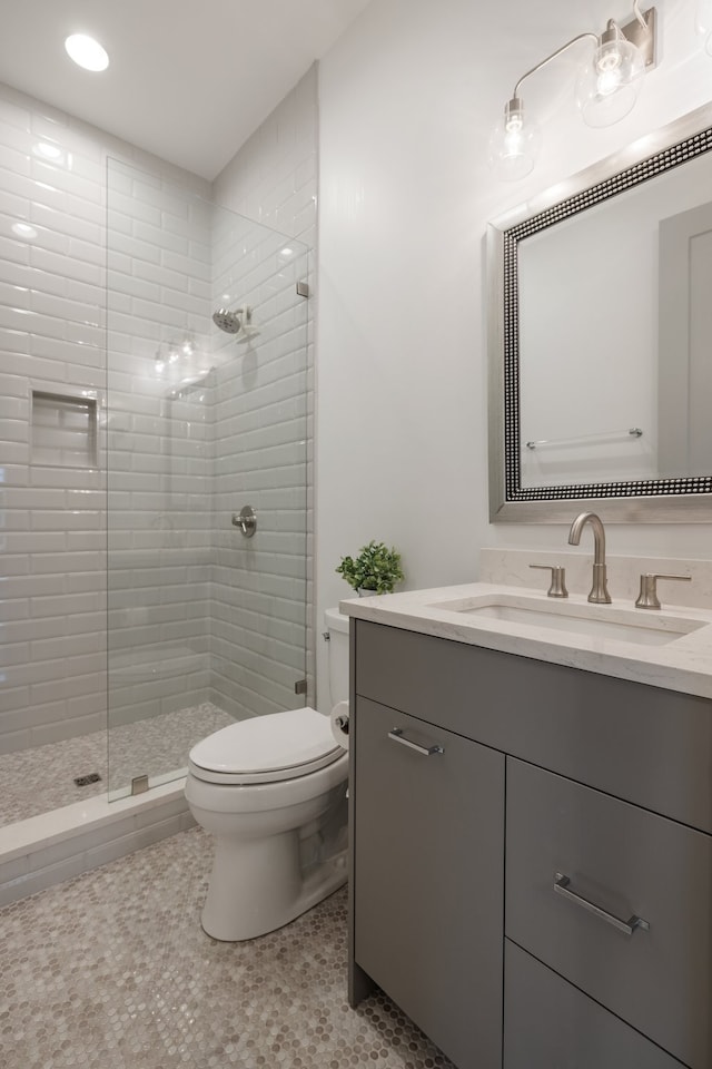 bathroom with a tile shower, vanity, tile patterned floors, and toilet