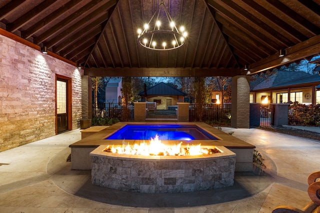 pool at dusk with a patio, an outdoor fire pit, and a gazebo