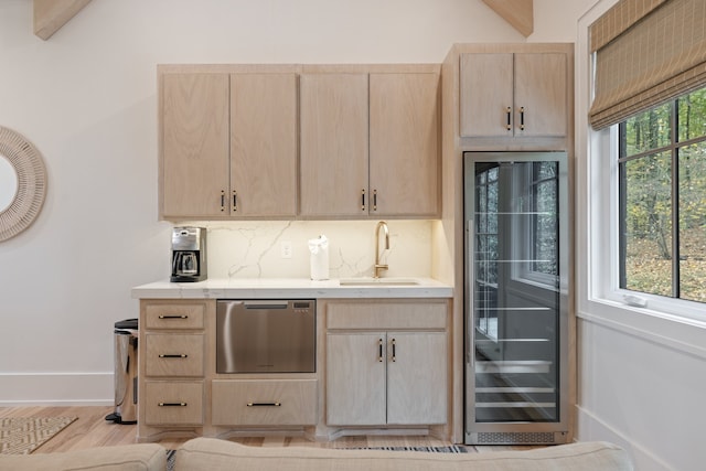 kitchen featuring light brown cabinetry, a wealth of natural light, beverage cooler, and sink