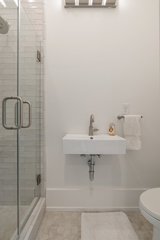 bathroom featuring toilet, walk in shower, sink, and tile patterned floors