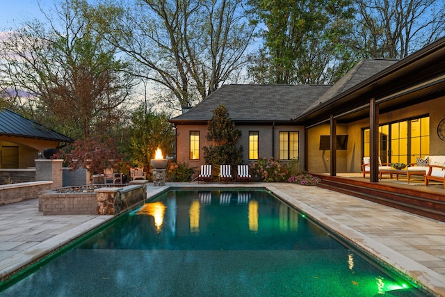 pool at dusk with a patio area and outdoor lounge area