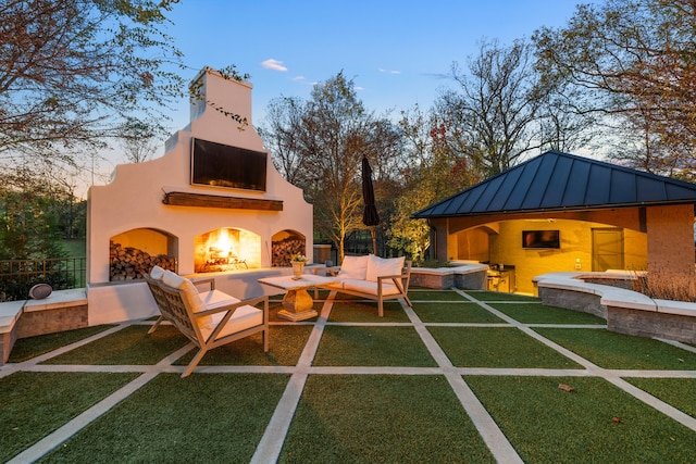 playground at dusk featuring a lawn, a patio, and an outdoor living space with a fireplace