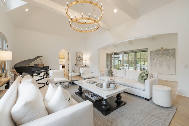 living room featuring lofted ceiling with beams, light hardwood / wood-style floors, and an inviting chandelier