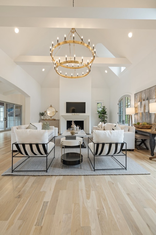 living room with light hardwood / wood-style floors, plenty of natural light, high vaulted ceiling, and a notable chandelier