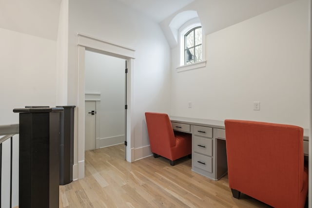 home office with built in desk, lofted ceiling, and light hardwood / wood-style floors