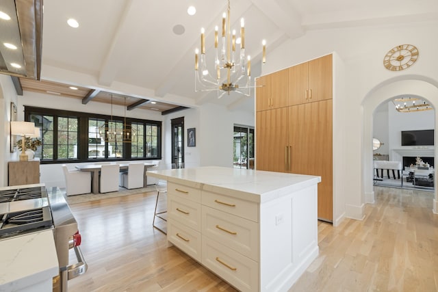 kitchen featuring light stone countertops, pendant lighting, light hardwood / wood-style floors, a breakfast bar area, and a spacious island