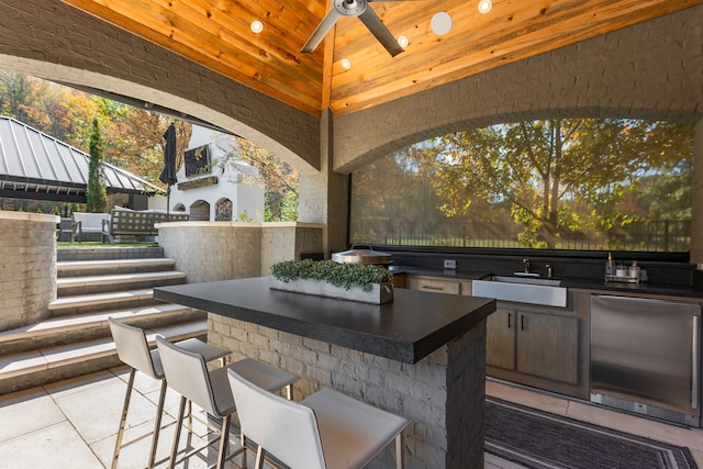 view of patio with a wet bar, a gazebo, ceiling fan, and exterior kitchen