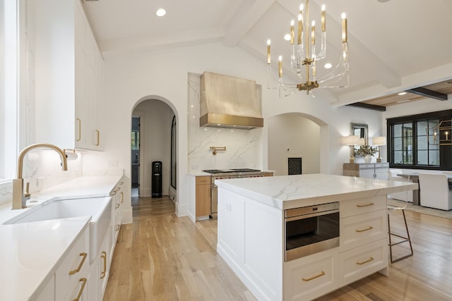 kitchen featuring wall chimney range hood, light hardwood / wood-style flooring, appliances with stainless steel finishes, and a center island