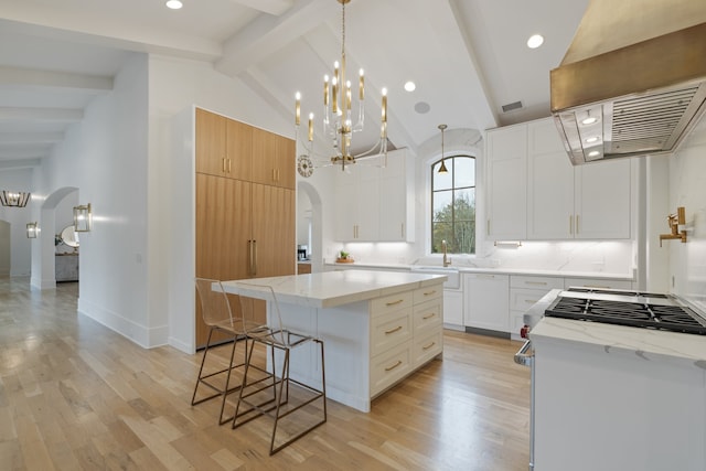 kitchen with beam ceiling, white cabinetry, light hardwood / wood-style flooring, and a center island