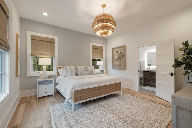 bedroom with light wood-type flooring, ensuite bath, and multiple windows