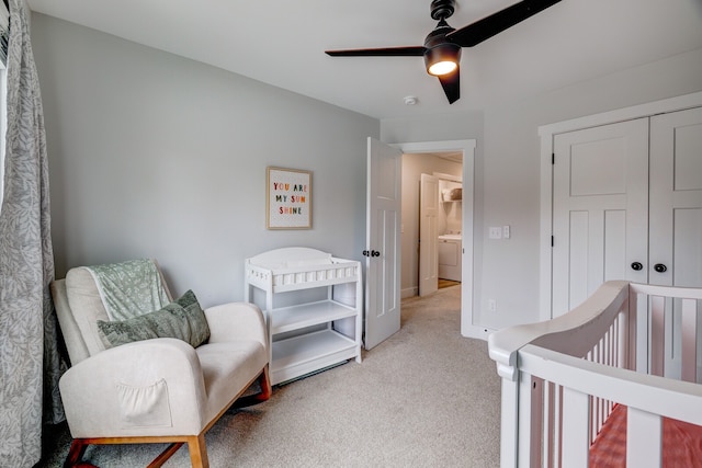 carpeted bedroom with a nursery area, ceiling fan, a closet, and washer / clothes dryer