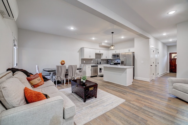 living room with a wall unit AC, light hardwood / wood-style floors, and sink