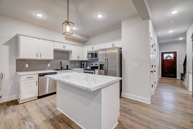 kitchen featuring stainless steel appliances, a kitchen island, sink, light hardwood / wood-style floors, and white cabinets