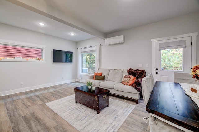 living room featuring a wall unit AC, beam ceiling, and light wood-type flooring