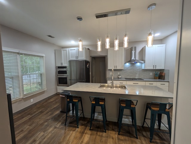 kitchen with stainless steel appliances, wall chimney exhaust hood, white cabinetry, and sink