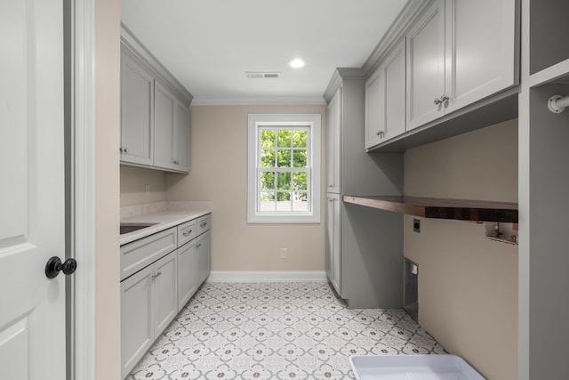 laundry area with hookup for an electric dryer, cabinets, crown molding, and sink