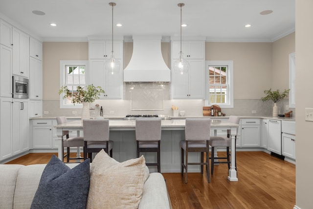 kitchen featuring white cabinetry, hanging light fixtures, and premium range hood